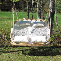 Double wide Cobble Mountain hammock chair hanging in a yard made of red oak and white rope