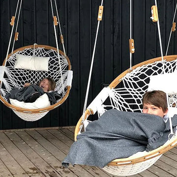 Two Cobble Mountain hammock chairs made of red oak and white rope with two little boys nestled in them