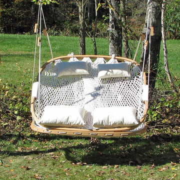 Double wide Cobble Mountain hammock chair hanging in a yard made of red oak and white rope 