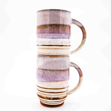 Side photo of stacked pair of stoneware mugs with pink and cream striped glaze handmade by Allison Morrissey