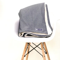 Denim Blanket Company herringbone denim blanket with cream fleece lining styled on a chair