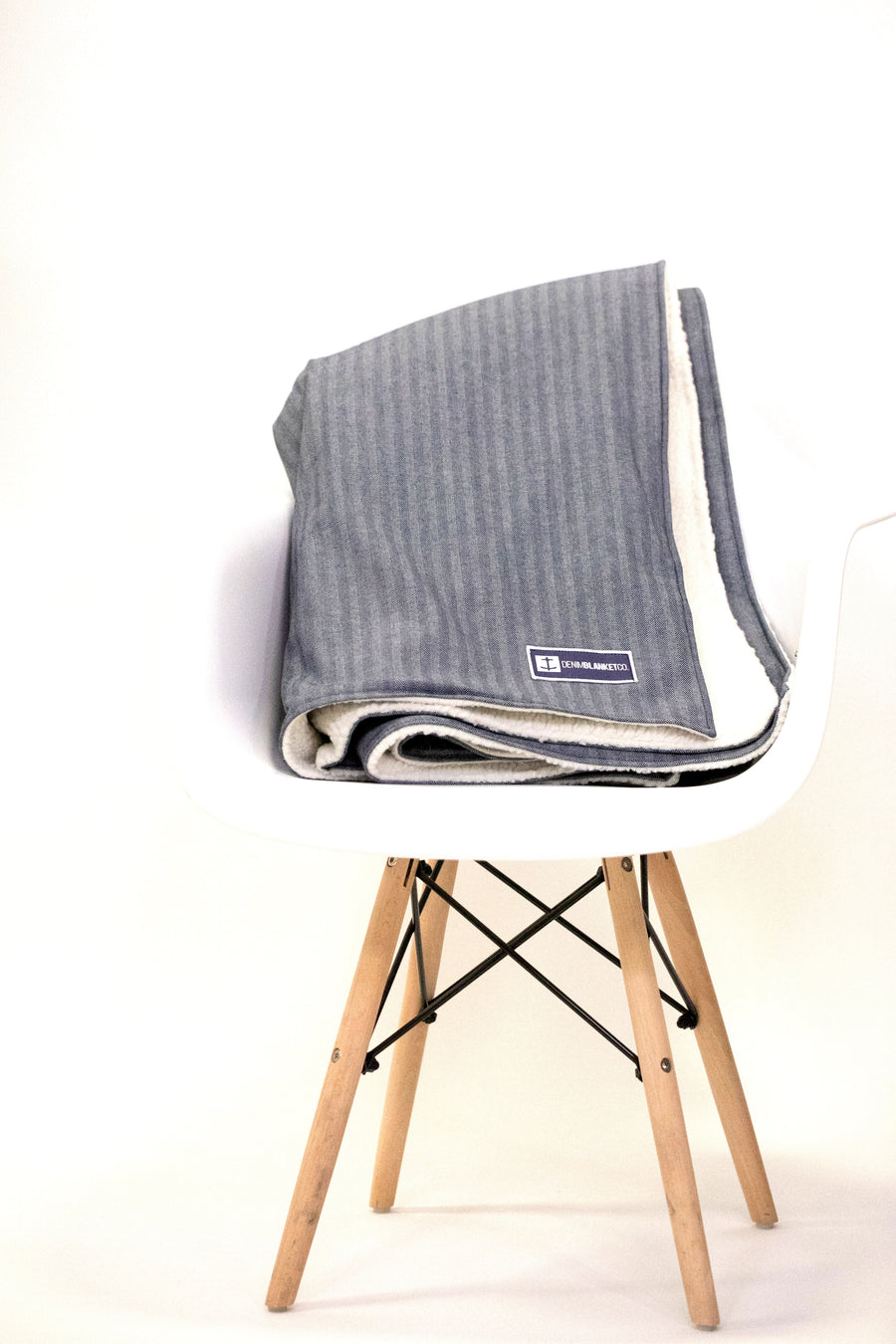 Denim Blanket Company herringbone denim blanket with cream fleece lining styled on a chair