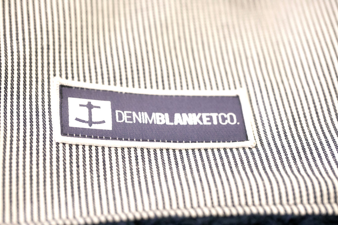 Logo shot of Denim Blanket Company logo on blue seersucker denim blanket with navy fleece lining