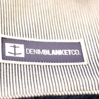 Logo shot of Denim Blanket Company logo on blue seersucker denim blanket with navy fleece lining